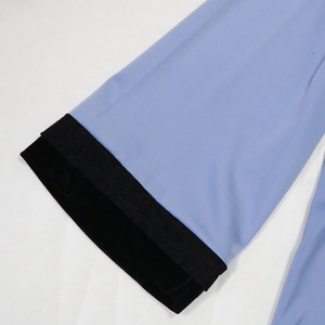 Detail of light blue dress with black lace trim and velvet cuffs showing rich fabric texture