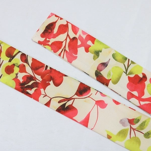 Detailed view of floral printed satin fabric straps with green and red leaf patterns