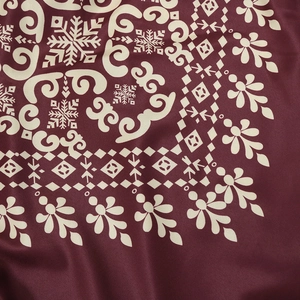 Detailed view of dark red jalabiya fabric with snowflake and mandala print patterns