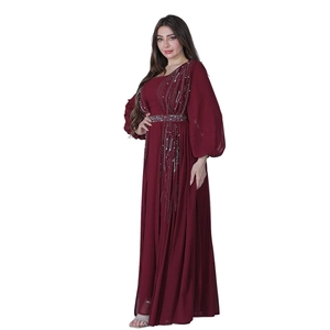 Detailed view of rhinestone fringe and beadwork on the waist of a burgundy evening gown