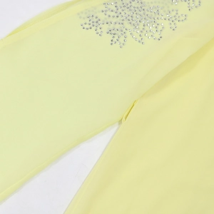 Detailed macro view of sparkling silver rhinestones on light yellow chiffon fabric