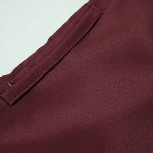 Macro detail of burgundy jalabiya dress featuring premium twill weave and reinforced stitching
