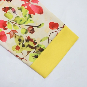 Detailed macro view of floral print fabric with bright yellow trim on a light beige dress