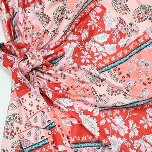 Detail of red paisley print dress showing fabric texture and adjustable side knot tie