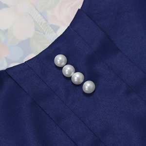 Dettaglio dell'abito blu scuro con texture plissettata e bottoni in perla bianca