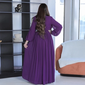 Detail of elegant purple long-sleeved evening gown featuring pleated skirt and back tie design