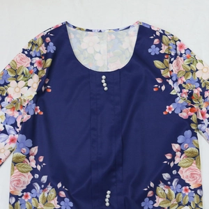 Dettaglio della tunica floreale blu navy con bottoni di perle e stampe di rose