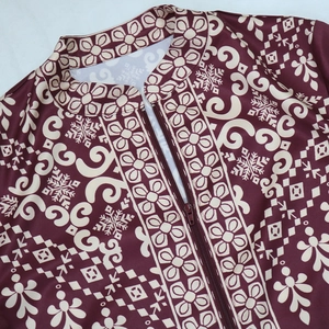 Detail of burgundy jalabiya dress showing zipper neckline and ethnic floral patterns