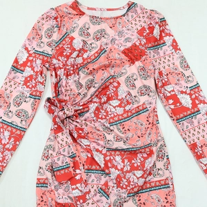 Detailed view of pink paisley floral patterns and waist tie on the long sleeve dress