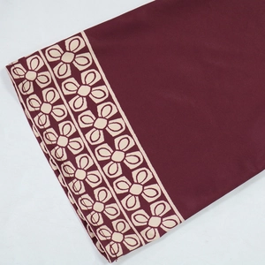 Detailed view of the burgundy fabric with elegant beige floral ethnic patterns on sleeves