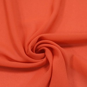 Texture macro del tessuto in chiffon rosso arancio che mostra il drappeggio morbido
