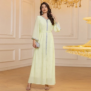 Detail of light yellow chiffon abaya with silver trim and buttons in elegant palace setting