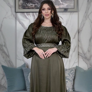 Détails de la robe en satin vert olive avec broderies de perles argentées à la taille et aux manches