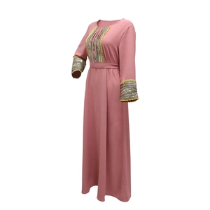 Macro detail of pink jalabiya dress featuring gold sequins and lace trim stitching