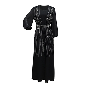 Detail of elegant black long-sleeved evening gown featuring vertical white beadwork accents