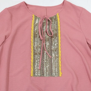 Detail of pink Jalabiya dress with sequin panel, lace trim, and tie neckline