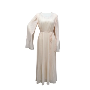 Détail d'une robe plissée rose montrant le col en V avec strass et la ceinture