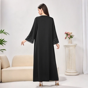 Detail of elegant black long Abaya dress featuring white dotted patterns on the sleeves