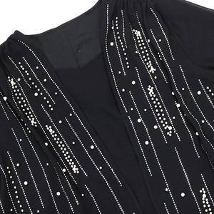 Close-up of elegant silver studs and white pearls on the black fabric of a formal gown