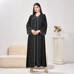 Detail of black Abaya featuring white piping and intricate geometric wreath patterns