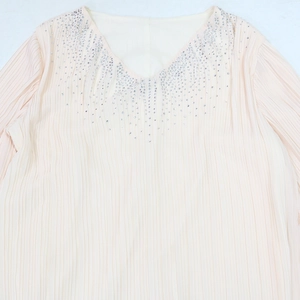 Vue détaillée du col en V avec strass argentés sur tissu plissé rose clair