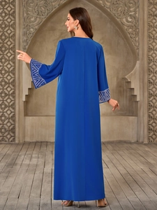 Detail of silver geometric rhinestone cuffs on a deep blue loose Muslim maxi dress