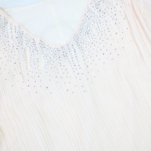 Détail du col en V avec strass argentés sur une robe de soirée plissée rose clair