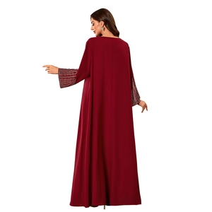 Detail of wine red dress sleeve featuring elegant rhinestone stripes and soft matte fabric