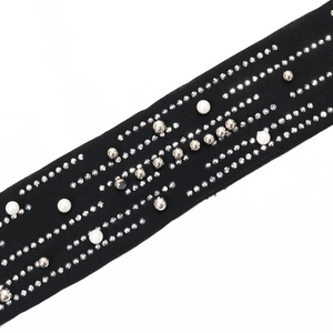 Detailed macro view of black fabric belt with rhinestones, pearls and metallic beads