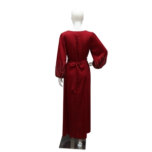 Détail de la robe en satin rouge avec ceinture à nœud et poignets en strass sur les manches