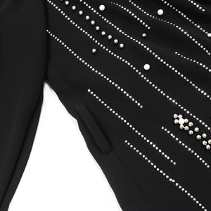 Detailed view of black gown fabric with elegant white pearls and silver metal rivets