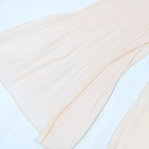 Vue macro détaillée de la texture plissée fine et de l'ourlet de la robe rose clair