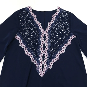 Macro detail of V-neckline embroidery and silver rhinestones on navy blue maxi dress