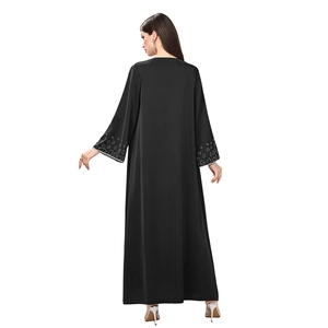 Detail of elegant black long-sleeve abaya featuring intricate white beadwork on the cuffs