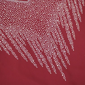 Macro view of sparkly rhinestones in feather pattern on red fabric dress
