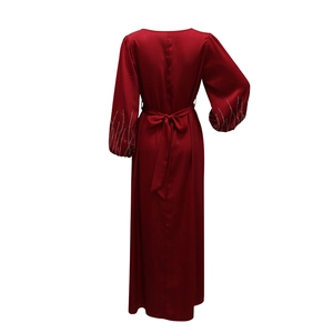 Détail du dos d'une robe longue bordeaux avec poignets en strass et ceinture nouée