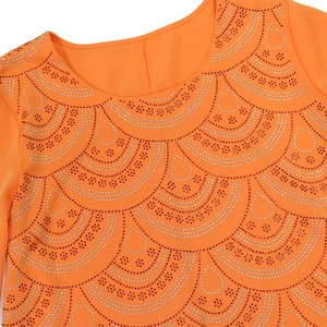 Détail de l'encolure d'une robe orange avec motifs de strass en forme d'écailles