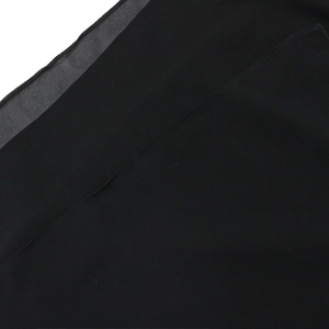 Detailed close-up of black chiffon evening gown fabric with fine stitched hem finish
