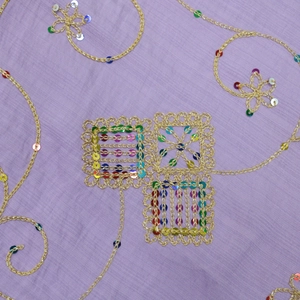 Detail of golden embroidery and colorful sequins on purple long robe fabric