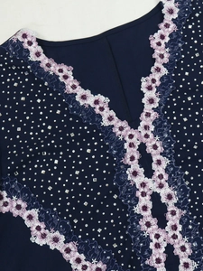 Close-up of V-neckline with purple floral embroidery and rhinestones on navy dress