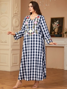 Detail of colorful floral embroidery on blue and white gingham long sleeve maxi dress