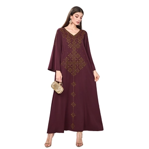 Détail d'une robe longue à col en V avec broderies dorées complexes et manches longues