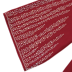 Close-up of sparkling V-shaped rhinestones on elegant burgundy loose-fit dress fabric