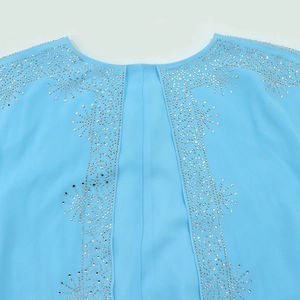 Macro detail of silver rhinestones in starburst pattern on light blue chiffon dress