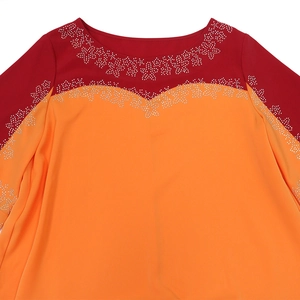 Détail de la robe longue pour femme avec contraste rouge-orange et strass en étoile