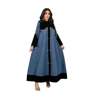 Detail of velvet abaya with sequin embroidery and decorative buttons on grey-blue fabric