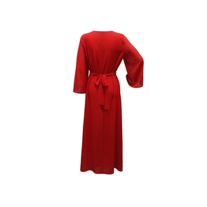 Détail de la robe de soirée rouge avec manches longues et ceinture à boucle métallique