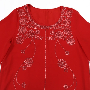 Détail d'une robe de soirée rouge avec motifs floraux en strass argentés et col rond