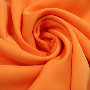 Gros plan sur un tissu textile orange vif montrant une texture fine et un beau drapé