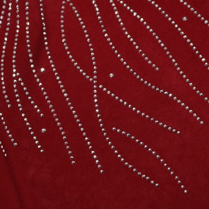 Détail macro de strass argentés en forme d'étoile sur le tissu rouge foncé d'une robe